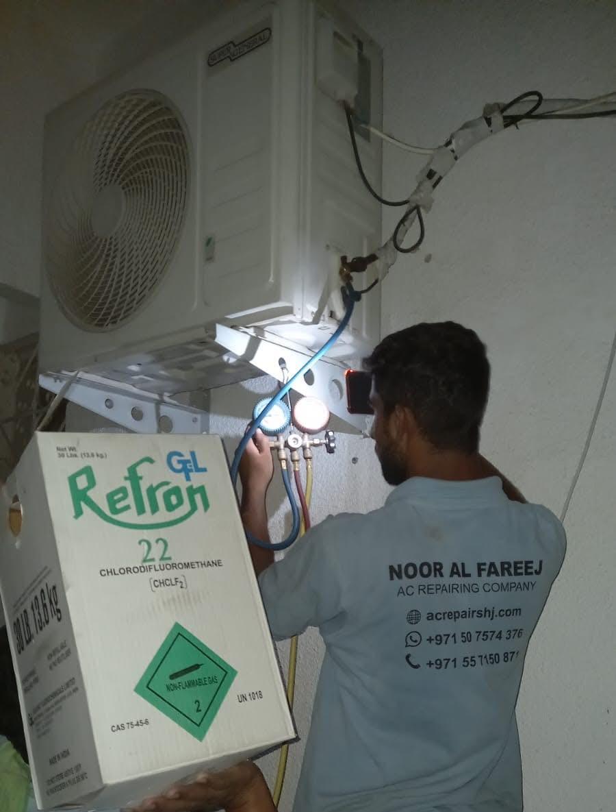 Noor Al Fareej technician recharging refrigerant on a split AC condenser in Sharjah