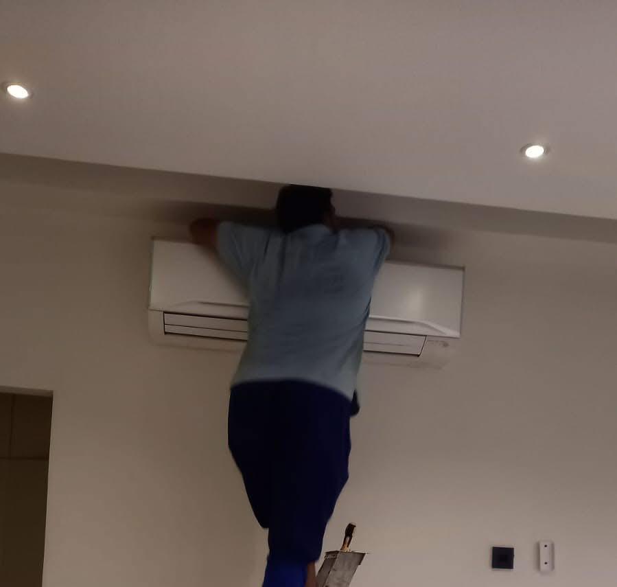 Technician servicing a wall-mounted split AC indoor unit in a Sharjah home