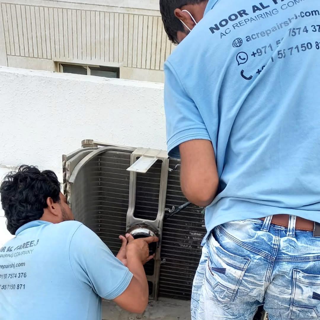 Two Noor Al Fareej technicians repairing a split AC condenser coil in Sharjah